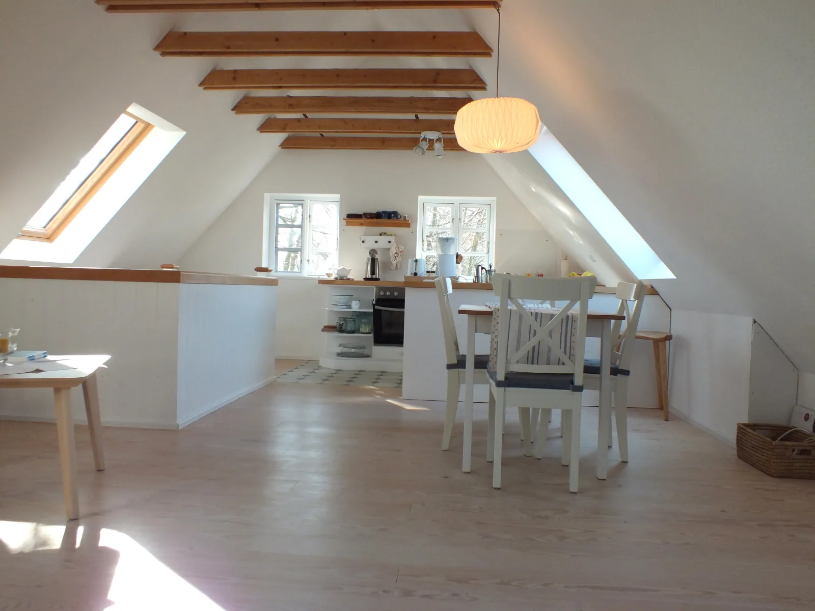 Offener Wohnraum der Ferienwohnung mit Esstisch und Dachbalken